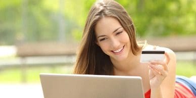 A woman smiles while looking at her laptop.